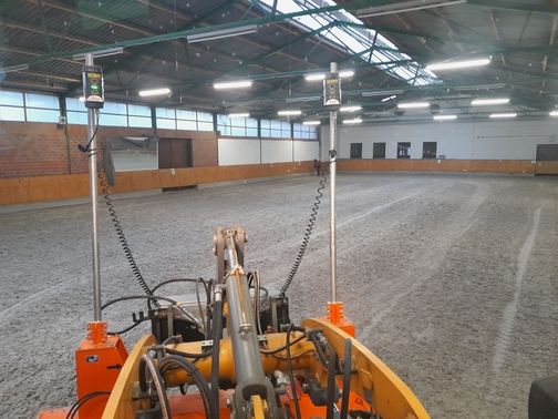 Maschine bei der Reitplatzpflege in einer Reithalle